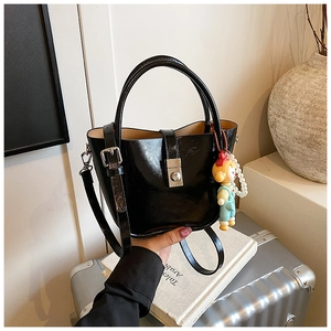 Detail of black glossy leather bucket bag with silver buckle and pearl charm accessory