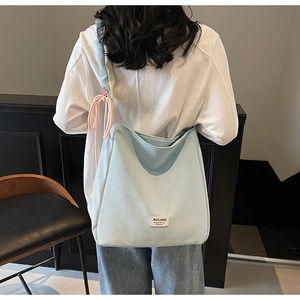 Close-up of light blue tote bag featuring MULAIDI logo tag and pink knot accent