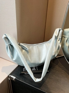 Minimalist mint green hobo bag with knotted strap and pleated texture on black books