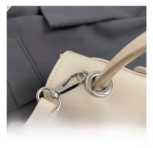 Detail of silver metal hook and premium leather strap on minimalist beige handbag