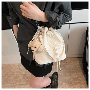 Detail of white water-ripple bucket bag with drawstring and plush toy dog charm