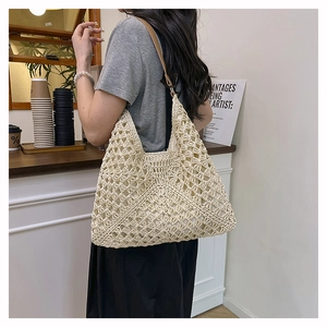 Close-up of cream handmade crochet straw tote bag with diamond mesh texture and leather strap