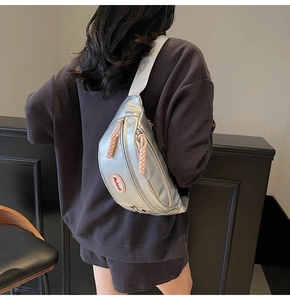 Dettaglio del marsupio argento con zip rosa intrecciata ed etichetta del marchio Mulaidi