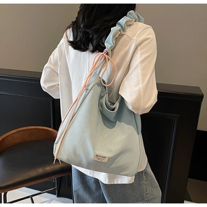 Detail of light blue tote bag featuring pleated shoulder straps and pink drawstring accents