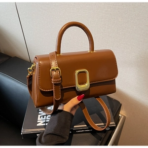 Détail d'un sac à main marron foncé avec boucle dorée élégante et texture cuir synthétique