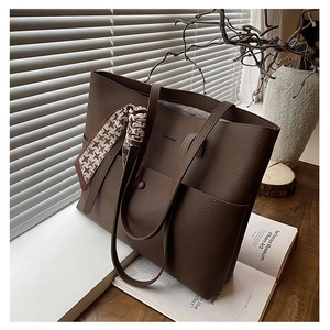 Close-up of brown lychee grain leather tote bag with silk scarf and front snap pocket