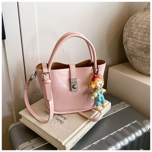Detail of a pink bucket bag with a cute doll pendant resting on vintage books