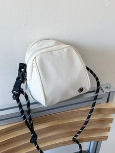 Modern white mini shell crossbody bag with double zippers and stylish woven rope strap