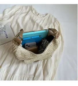 Top view of spacious straw bag interior with daily items and premium leather strap details