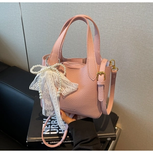 Detail of pink lychee leather handbag with lace pearl bow and gold hardware accents