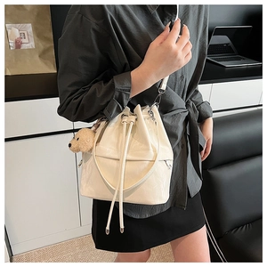 Detail of cream drawstring bucket bag with plush dog charm for daily commute