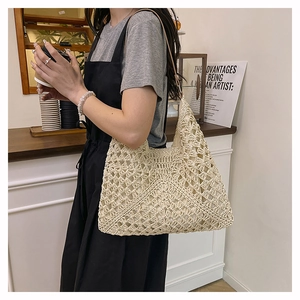 Detailed close-up of handmade hollow crochet patterns on a beige straw tote bag