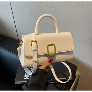 Détail du sac à main en cuir blanc cassé montrant la boucle dorée et la texture lisse