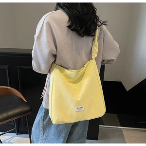 Detail of a bright yellow large canvas tote bag showing the wide shoulder strap and fabric label