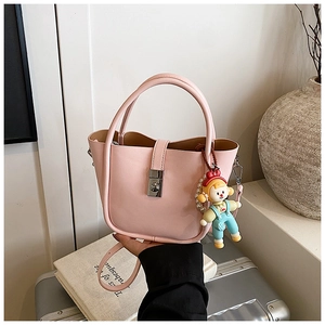 Pink bucket bag with silver twist lock and cute doll charm on a silver suitcase