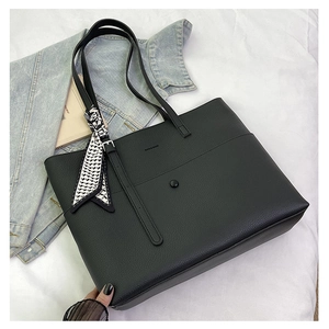 Macro detail of black tote bag featuring textured leather, front pocket, and chic silk scarf