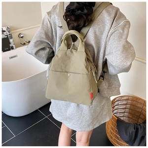 Light sage green nylon multipurpose sling bag worn as a backpack in modern setting