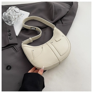 Close-up of cream crescent bag with lychee grain leather on a grey blazer suit