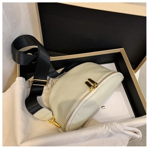 Detail of cream pebbled leather half-moon bag with gold dual zippers and wide nylon strap