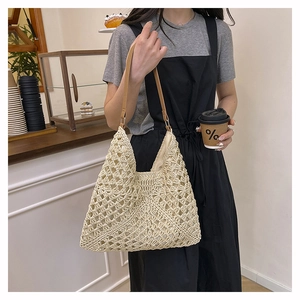 Detail of hollow crochet straw hobo bag with brown faux leather strap and beige lining