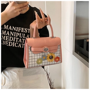 Detail of pink handbag with black and white plaid pattern and colorful 3D floral accents