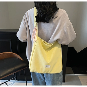 Detail of yellow canvas hobo bag showing the side pink drawstring and brand logo label