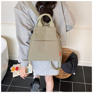 Rear view of a light green nylon crossbody bag with adjustable straps on a model