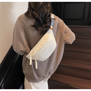 Detail of white canvas crescent fanny pack with woven zipper pulls and wide strap