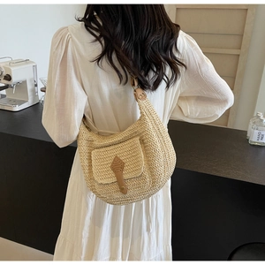Detailed texture of hand-woven beige straw shoulder bag with brown leather clasp detail