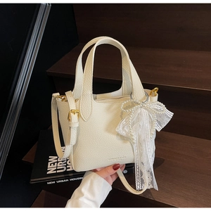 Detail of cream white pebbled leather mini tote bag with lace and pearl bow charm