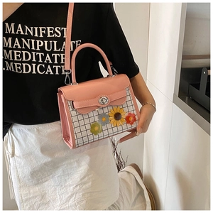 Detail of pink crossbody bag with knitted sunflowers and checkered pattern worn by a model