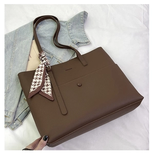Brown leather tote bag with logo embossing and houndstooth scarf on a white fabric