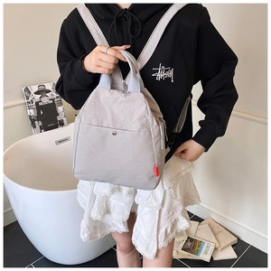 Detail of light grey multi-use chest bag with grey-blue handles and front snap pocket