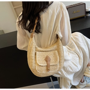 Detailed texture of hand-woven straw bag featuring brown leather buckle and front pocket