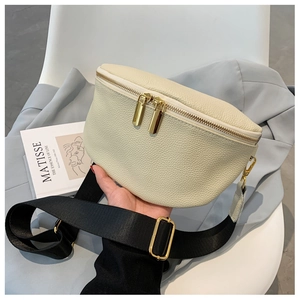 Close-up of beige pebble leather crossbody bag with dual gold zippers and black strap