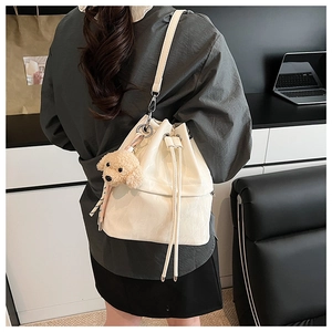 White drawstring bucket bag with teddy dog charm shown on a model's shoulder