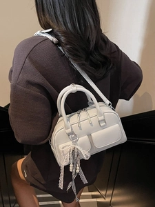 Light gray Boston mini bag with pearl charms and lace bow decorations on a female model