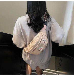Borsa a tracolla beige con toppa a cartone e tracolla rosa regolabile indossata sulla schiena