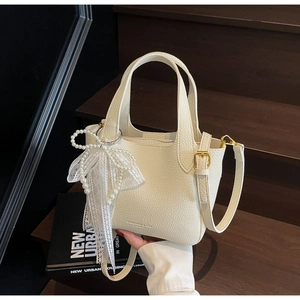 Detailed texture of white pebble leather bag with pearl lace bow and champagne gold metal