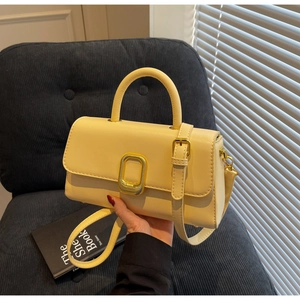 Gros plan d'un sac à rabat jaune clair avec boucle dorée sur fond de velours côtelé