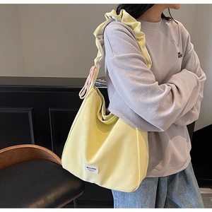 Detail view of a yellow tote bag featuring ruffled shoulder straps and pink drawstring accents