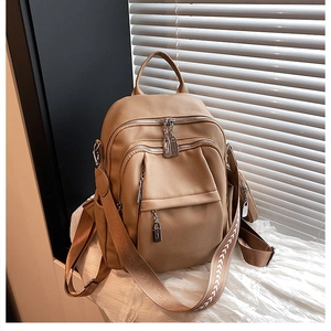 Close-up of khaki lychee grain leather backpack with vintage woven embroidered strap