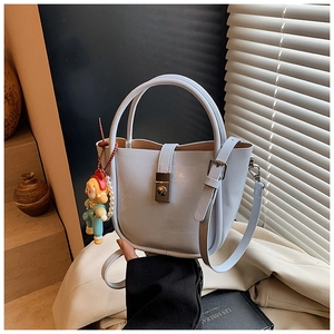 Detail view of light blue bucket bag with leather texture, metal buckle and cute charm