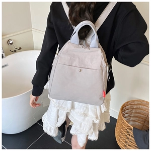 Detail of grey nylon multi-way chest bag with magnetic buckle and red fashion label