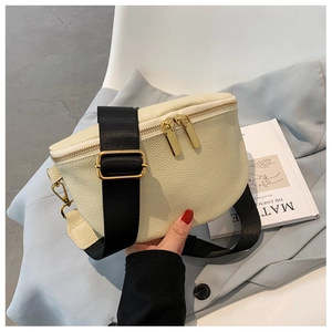 Detail of beige lychee leather crossbody bag with gold zippers and black nylon strap