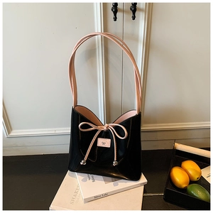 Détail du sac fourre-tout en cuir noir avec un nœud rose et de longues bandoulières