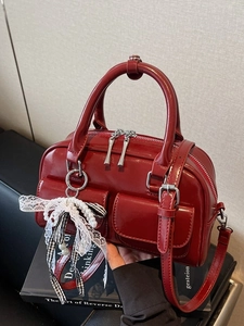 Glossy red patent leather Boston handbag with lace bow charm and crossbody strap