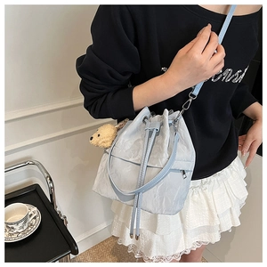 Close-up of light blue drawstring bucket bag with textured fabric and puppy charm