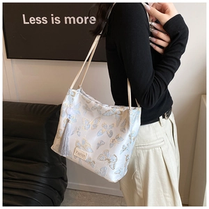 Close-up of elegant bucket bag with blue butterfly embroidery and a long grey tassel