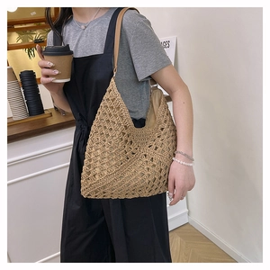 Detailed close-up of a hollow woven straw hobo bag with brown leather shoulder strap